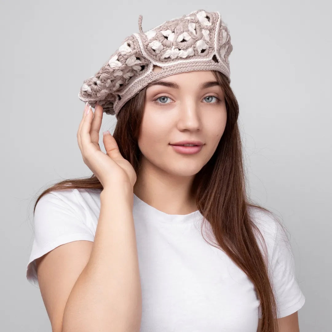 Woman wearing a decorative crochet beret against a plain background