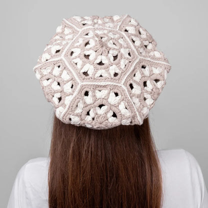 Person wearing a beige crochet hat against a gray background