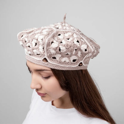 Woman wearing a beige crochet hat against a gray background