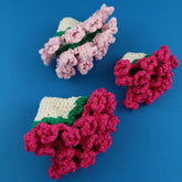 Three crocheted flower coaster on a blue background