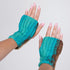 Turquoise and brown fingerless gloves worn on hands with a plain background